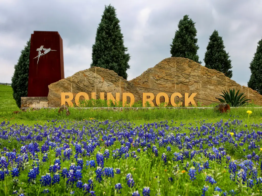 Welcome sign at Round Rock, a town in Texas, with bluebonnets in the foreground