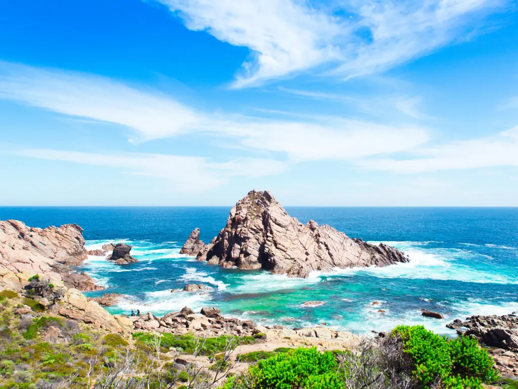 View of rugged rock formation rising above the ocean on a sunny day