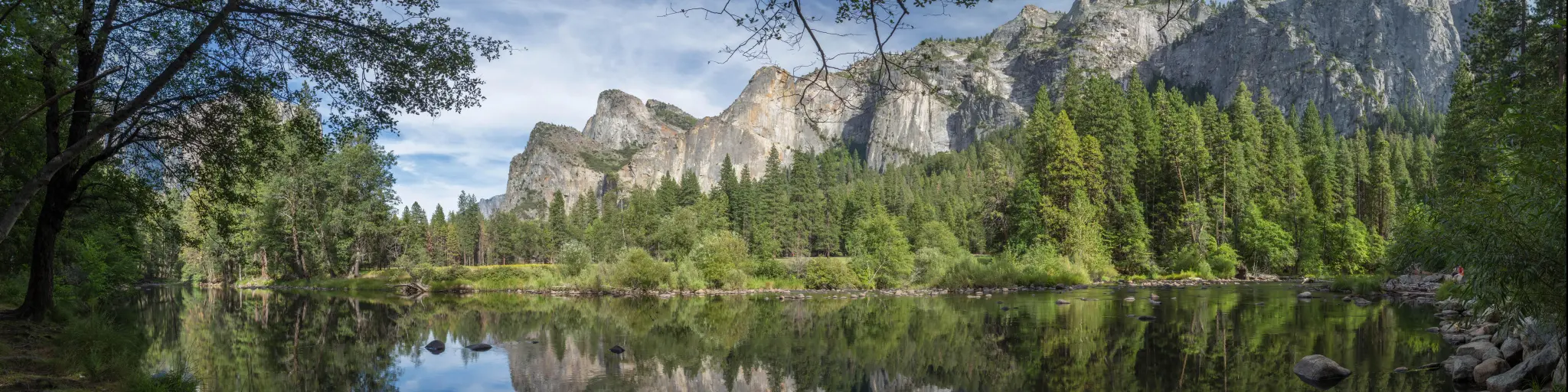 Panoramic view of Yosemite National Park with a lake in the foreground and blue sky above