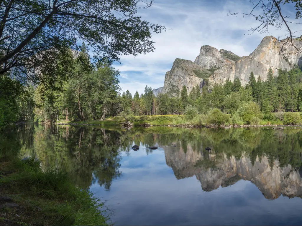 Panoramic view of Yosemite National Park with a lake in the foreground and blue sky above