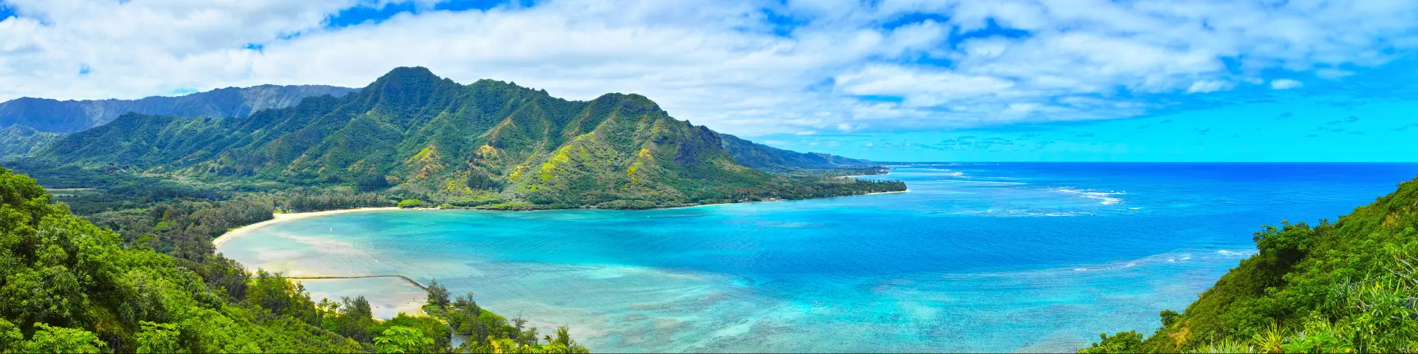 Panoramic view of the coastline from the hike to Crouching Lion Rock in Hawaii, with clear turquoise waters