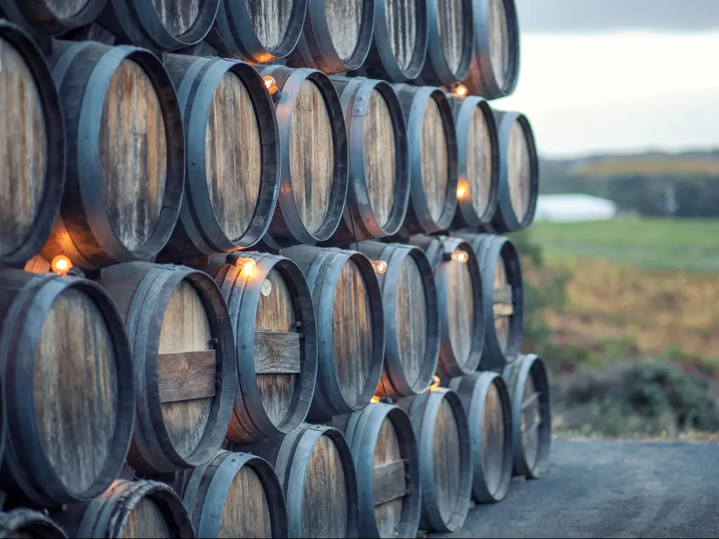 Stacked rustic oak barrels near a vineyard in California wine country, Napa Valley