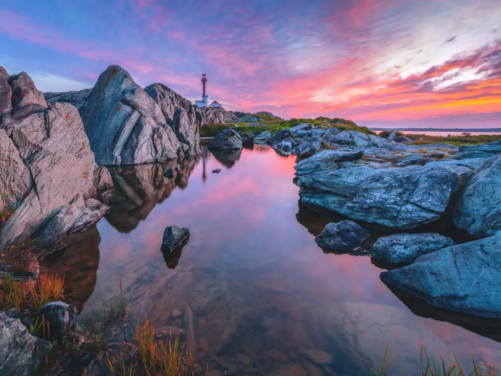 Beautiful pink sunset over the water with the lighthouse seen in the distance