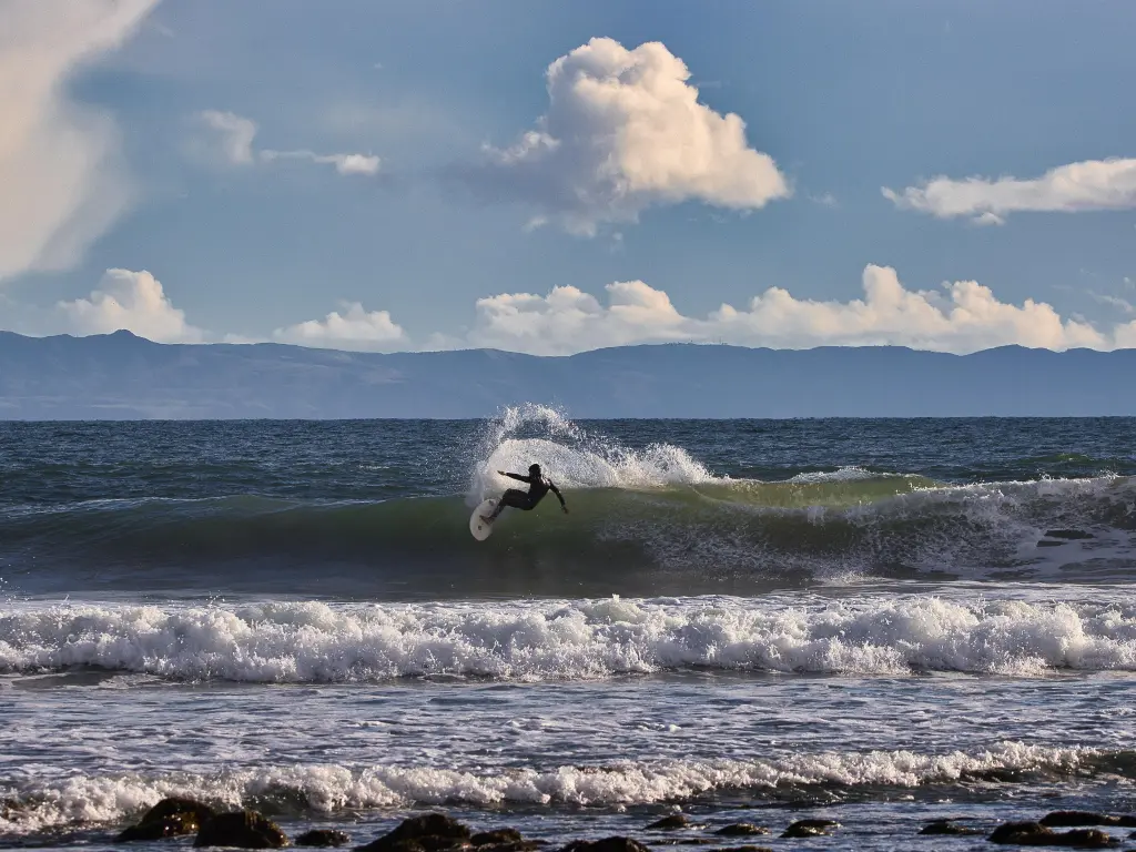 Surfer riding a wave on the ocean, partially cloudy day