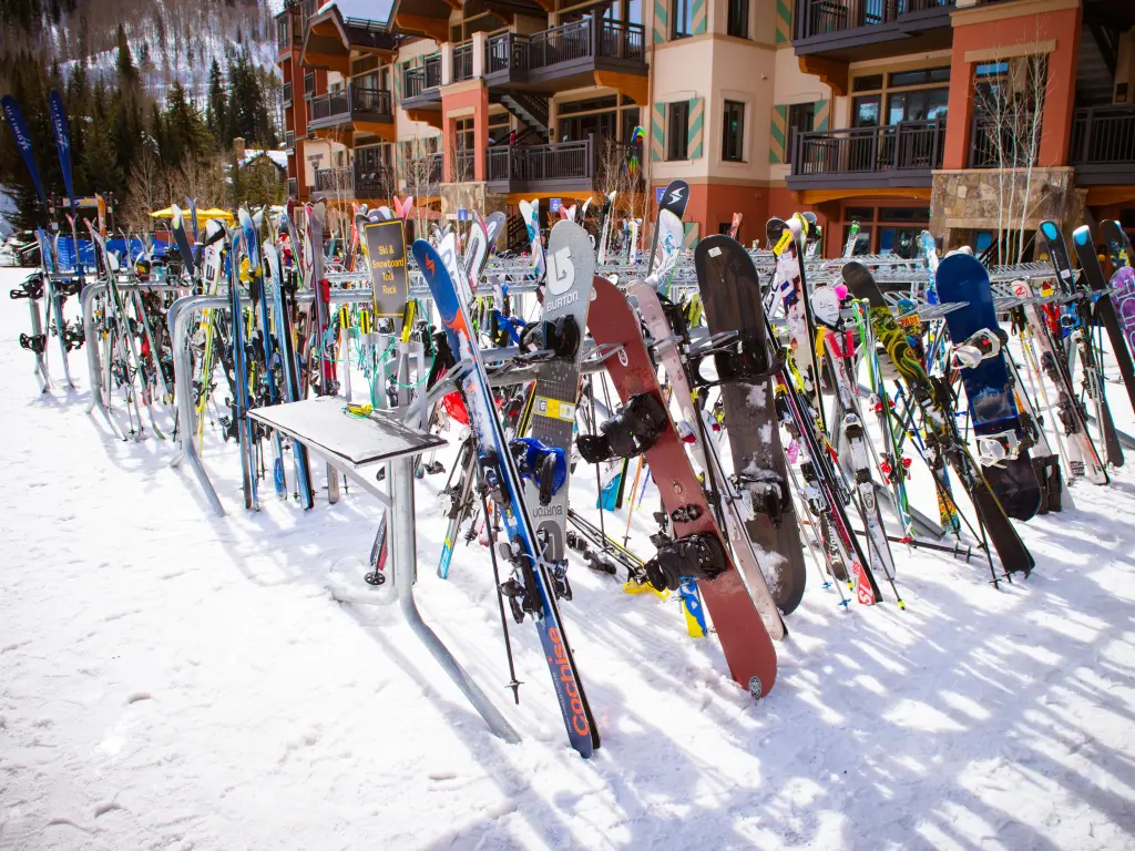  Snowboards and skis resting on stands outside at the ski resort