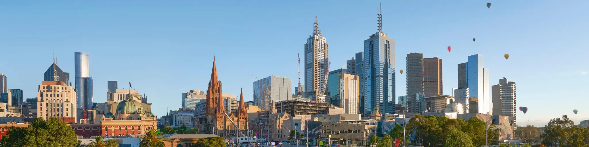 Panoramic view of city's skyline with hot air balloons in the sky