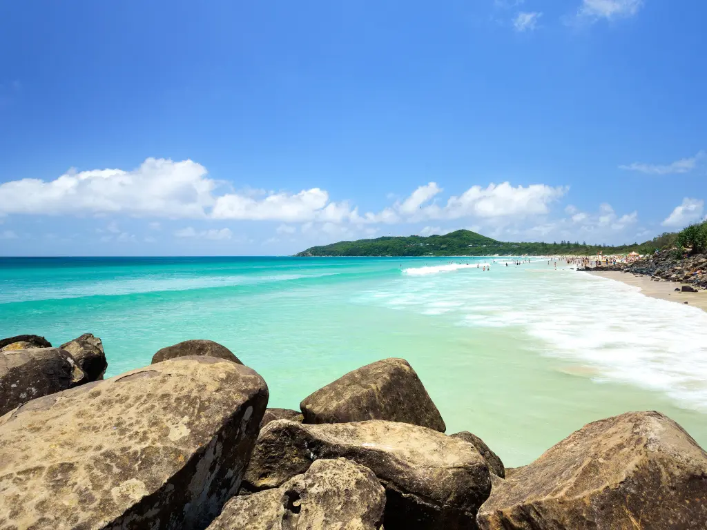 Beautiful turquoise waters of the ocean at the beach with big rocks in the foreground