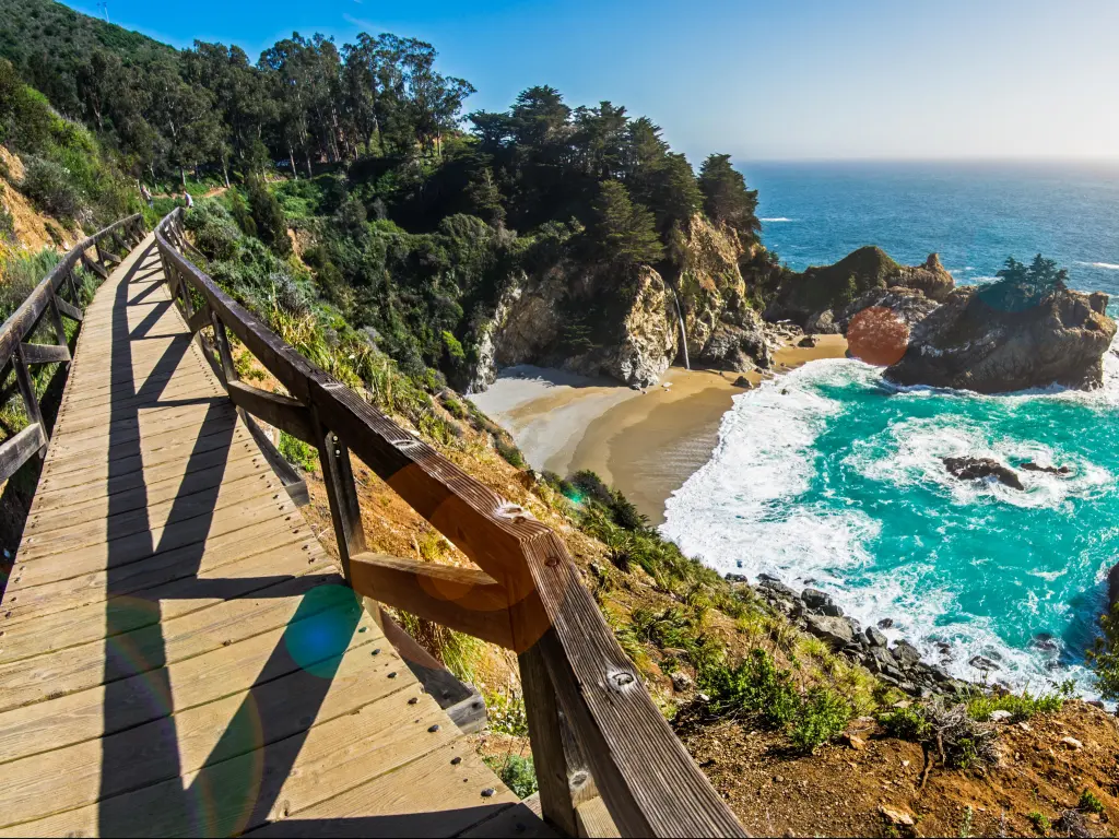 Board walk above small sandy cove with turquoise water and rocks