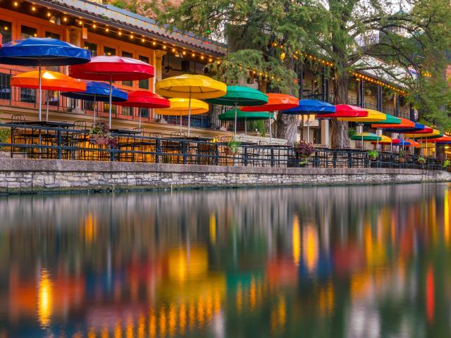 Colorful umbrellas by the famous River Walk, their reflections can be seen on the water