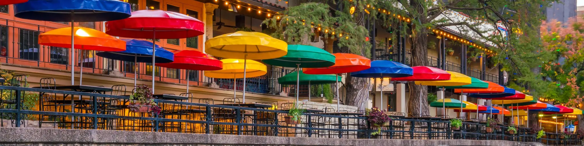 Colorful umbrellas by the famous River Walk, their reflections can be seen on the water