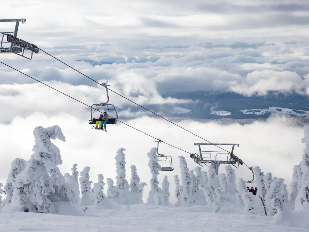 Chairlifts going up the slope on a cloudy day, snow covered surroundings