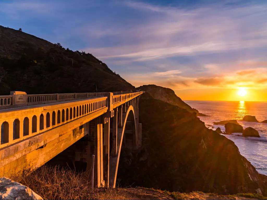 Bixby Creek Bridge, Pacific Coast Highway at sunset with an orange glow cast over the ocean
