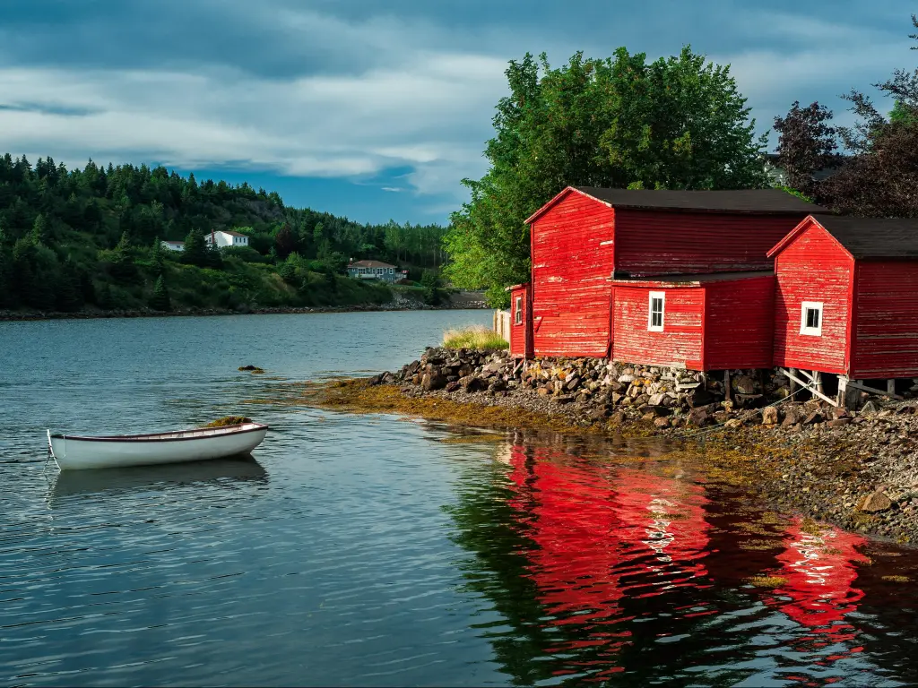 Red wooden buildings stand at the edge of the harbor at Conception Bay, Newfoundland, Canada