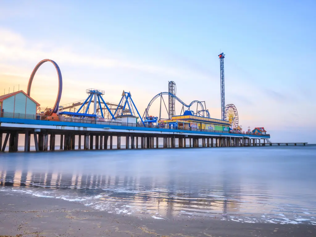 Sunrisee at the pier with theme park rides and roller coasters in the distance